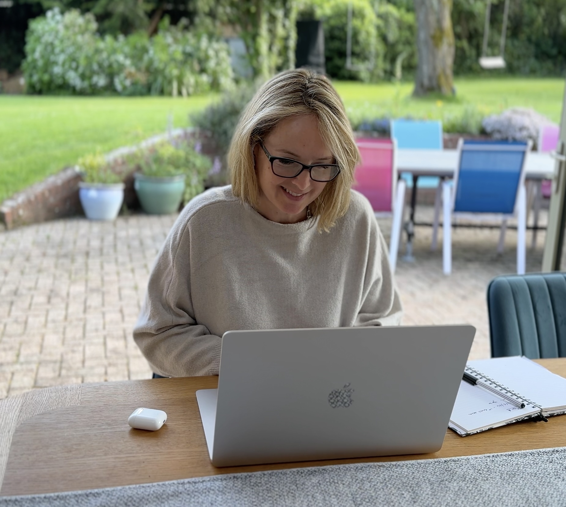 Sarah Ewen working on her laptop at a desk overlooking the garden